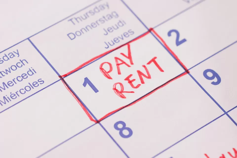 Close-up of 'Pay rent' note in red marker on day 1 of monthly calendar.